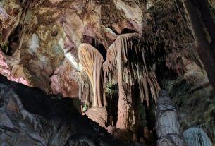 Stalactites and stalagmites in a cave with colorful lighting